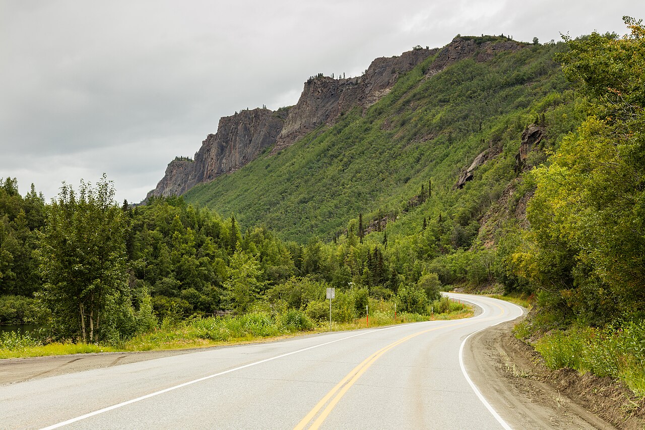 The Glenn Highway winding past green hillsides and rocky cliffs near Palmer, Alaska