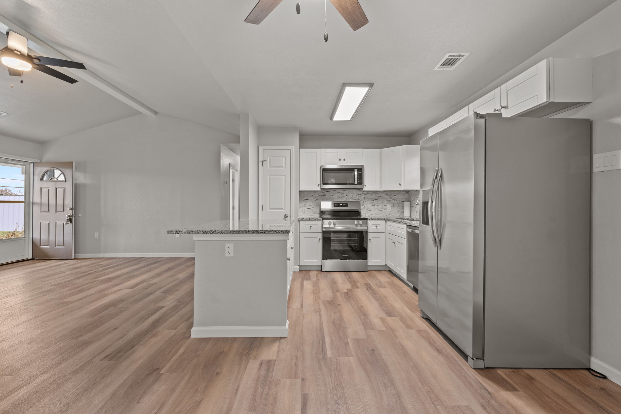 Renovated residential rental kitchen with white cabinets, stainless steel appliances and wood-look flooring