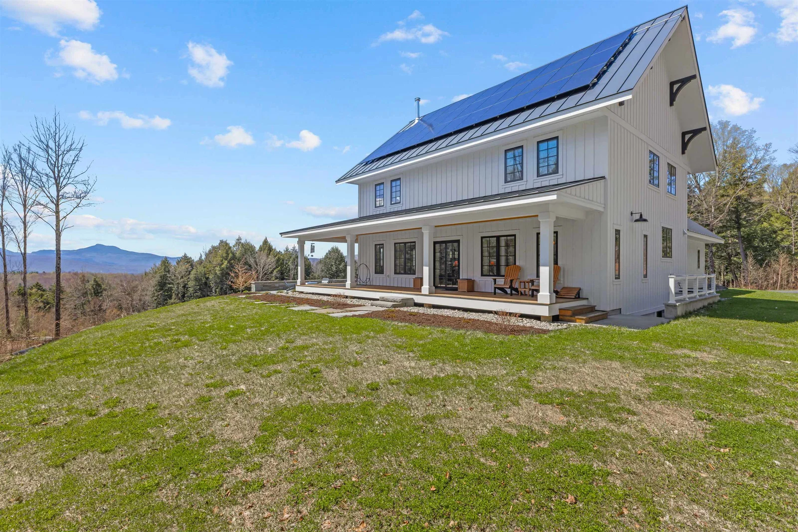 Custom Vermont home exterior with standing seam roof and landscaped grounds