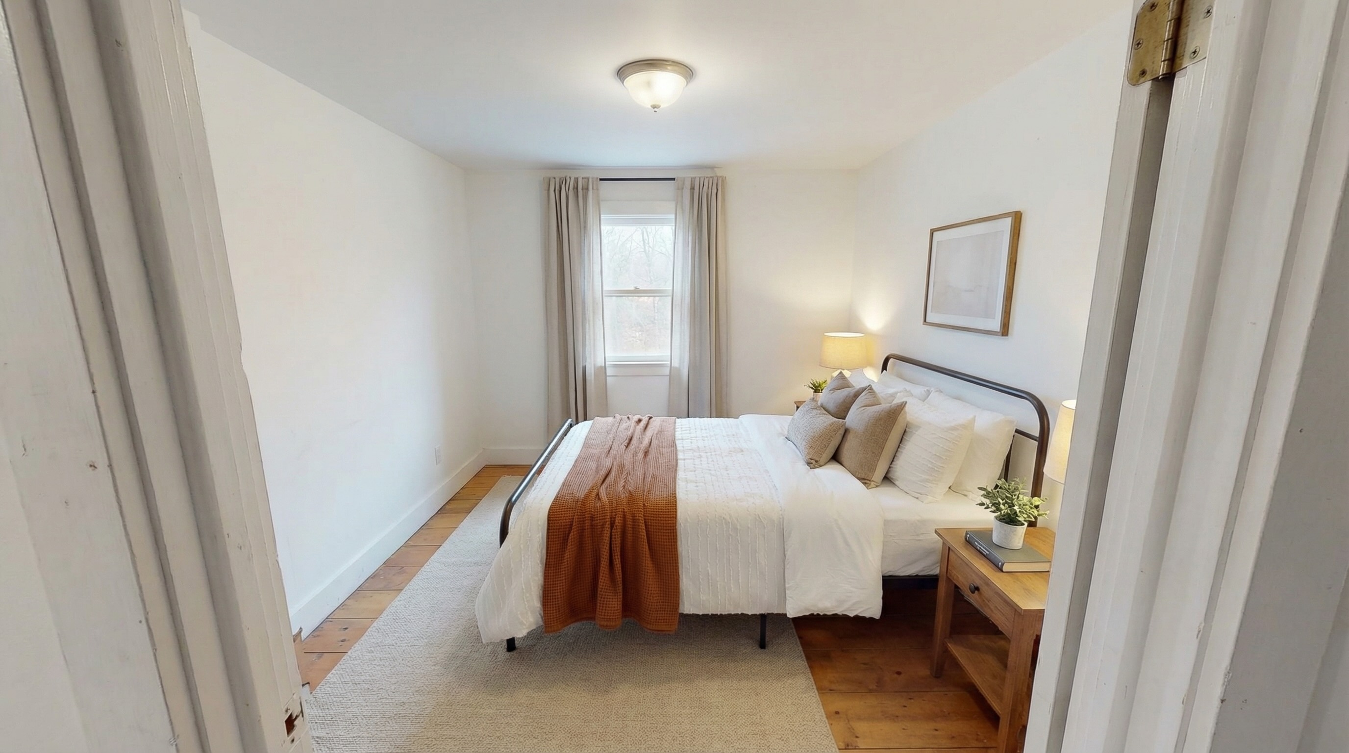 Professionally staged secondary bedroom with neutral bedding, nightstands, lamps, and cohesive warm styling
