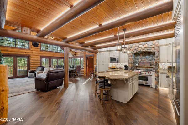 Open-concept log great room with stone fireplace and wall of windows at 1344 Buckhorn Loop, Flagstaff AZ