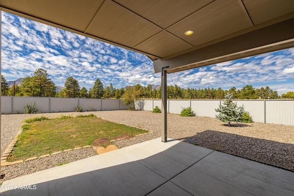 Covered patio overlooking large fully fenced backyard at 10226 Lundin Rd, Flagstaff, AZ