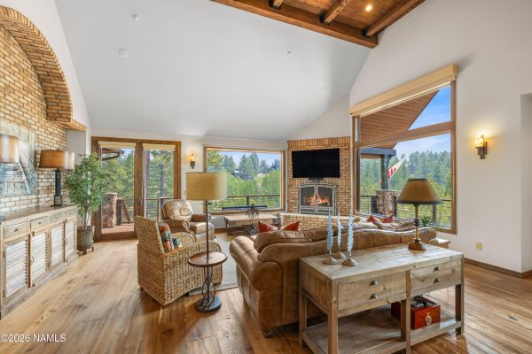 Great room at 3385 S Tourmaline Dr in Pine Canyon, Flagstaff, AZ with exposed beams, vaulted ceilings, and floor-to-ceiling brick fireplace