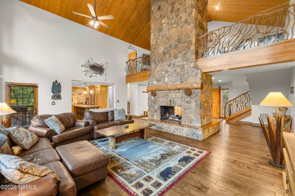 Vaulted great room with dual-sided natural stone fireplace and birch hardwood floors in a Flagstaff AZ luxury home