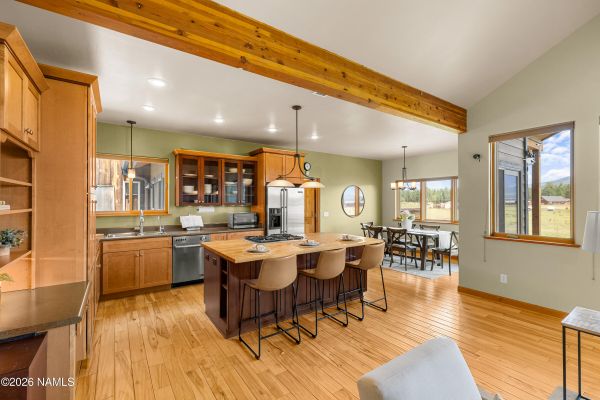 Open kitchen with exposed beams and solid birch flooring inside a custom luxury home in Flagstaff, AZ