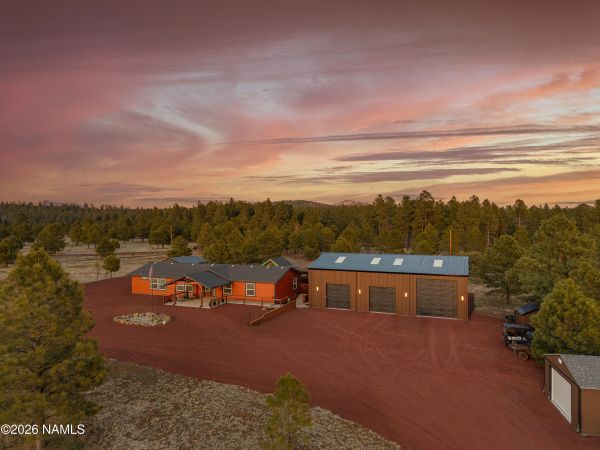 Luxury mountain home exterior on fenced acreage with covered porch and forest surroundings in Northern Arizona