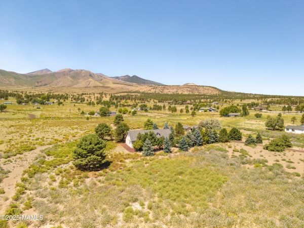 Mountain view home in Flagstaff AZ with spruce and pine tree-lined driveway on 2.69 acres featuring peaceful Northern Arizona surroundings and San Francisco Peaks views.