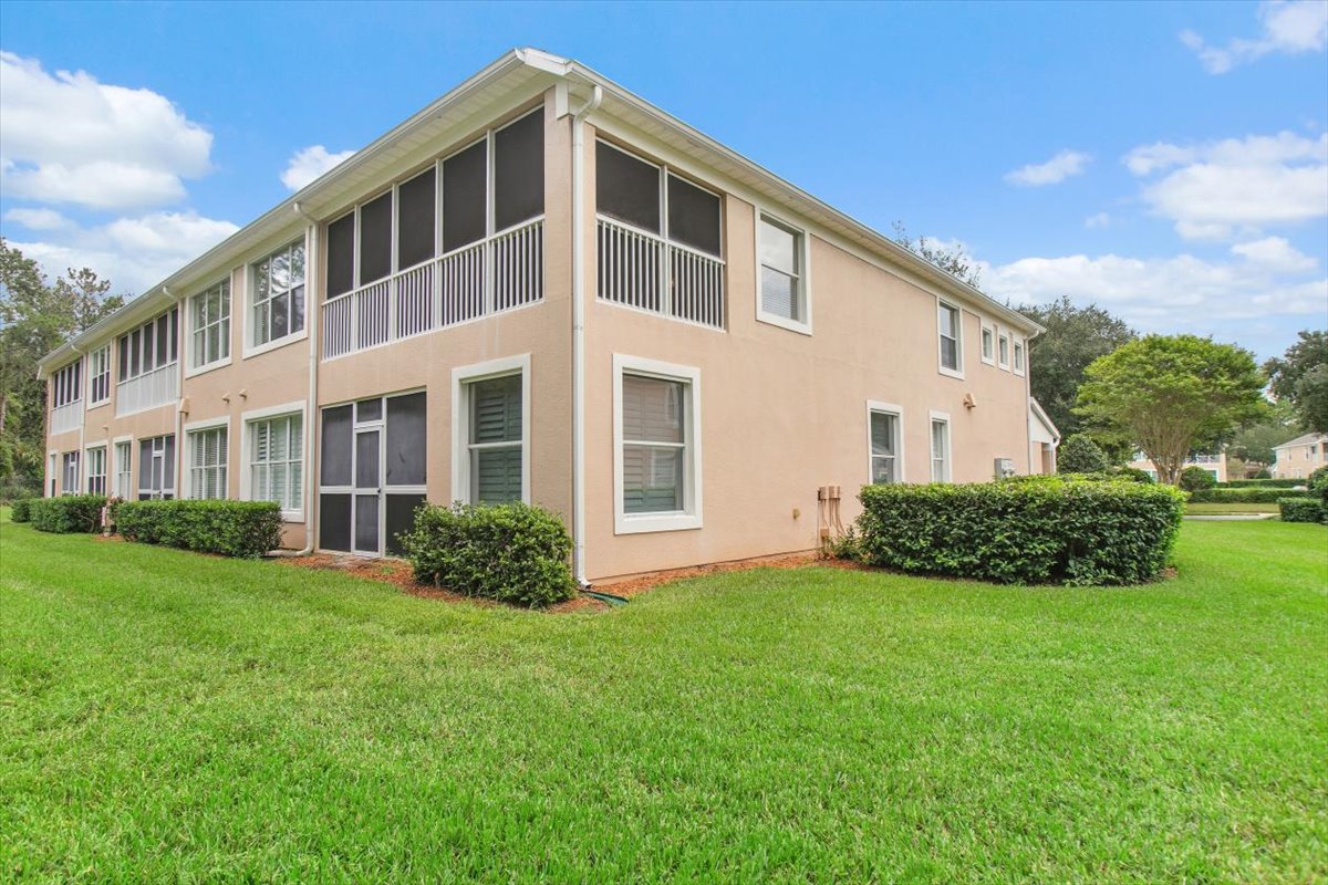 Rear exterior of 8555 Little Swift Circle showing the screened lanai, open lawn and mature trees in The Tides at Sweetwater by Del Webb, Jacksonville Florida