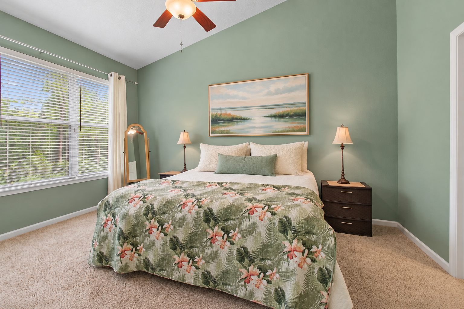Primary bedroom with vaulted ceiling and views toward the lawn and mature trees at 8555 Little Swift Circle in Sweetwater