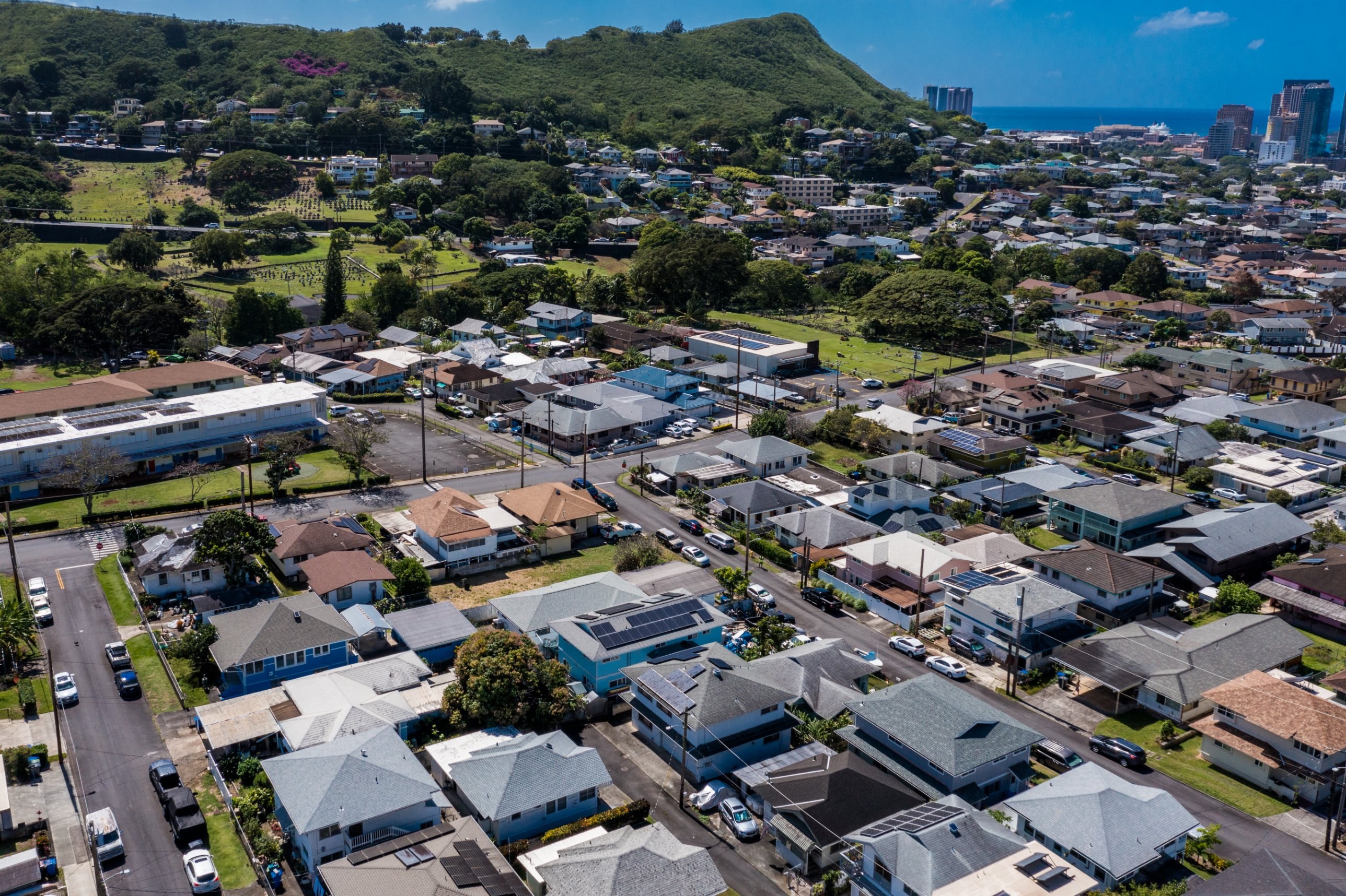 Aerial view of a Honolulu hillside neighborhood with the harbor and high-rises beyond