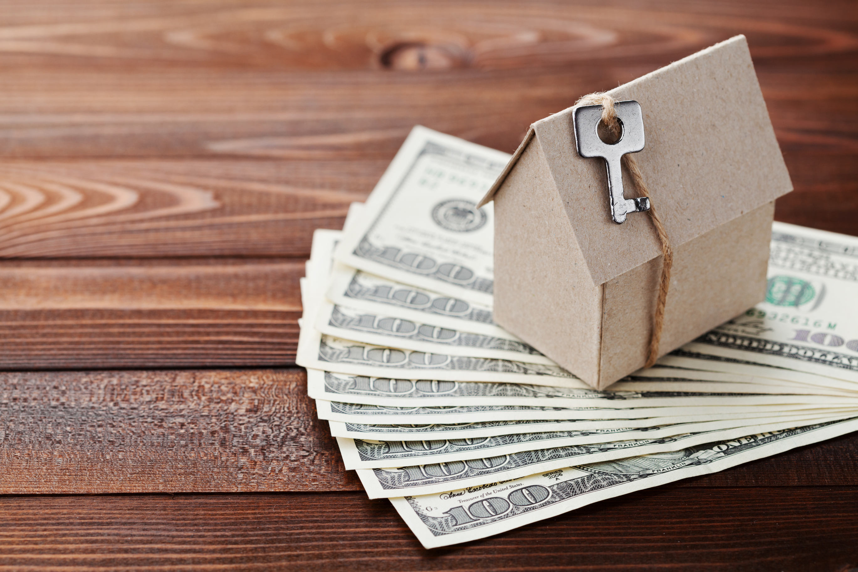 House model and key resting on money to represent earnest money