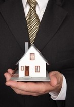 person holding a small house in a suit and tie