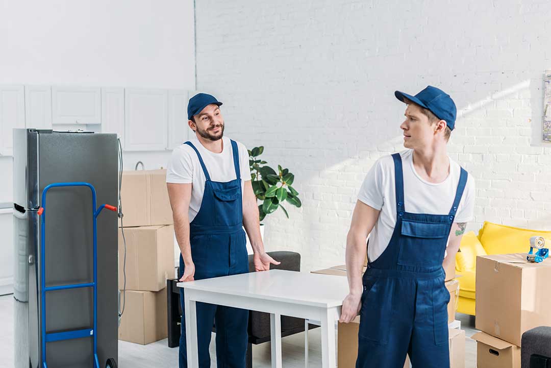 PIC - TWO MOVERS CARRYING A TABLE: Savvy buyers also have the good news of more affordable quotes from movers during the off peak winter market.