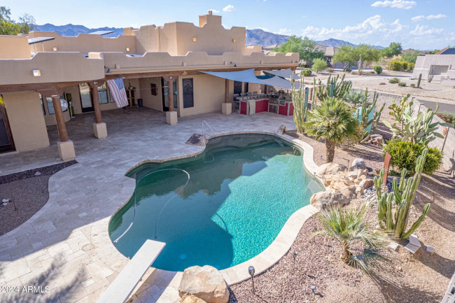 Stunning RV Garage Home for sale in Buckeye Arizona, the image shows the backyard with a pool, outdoor kitchen, amazing patio
