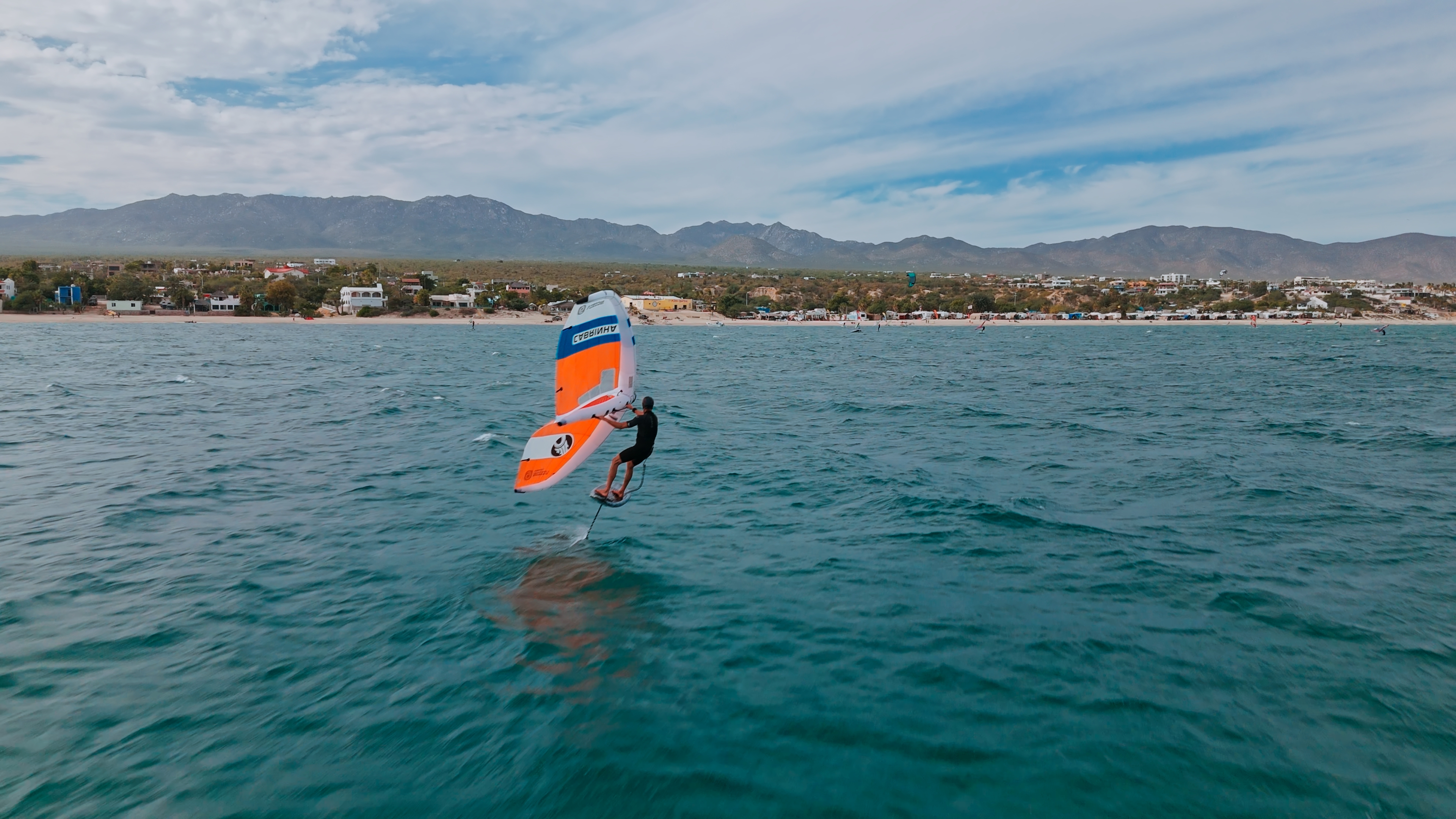 A wing foiler on the bay at La Ventana, Baja California Sur, Mexico, with the town and mountains behind