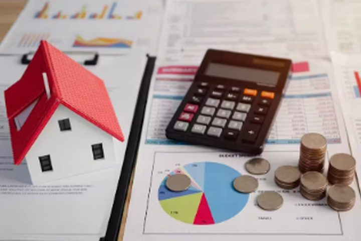 Model house beside a calculator, coins and a loan chart
