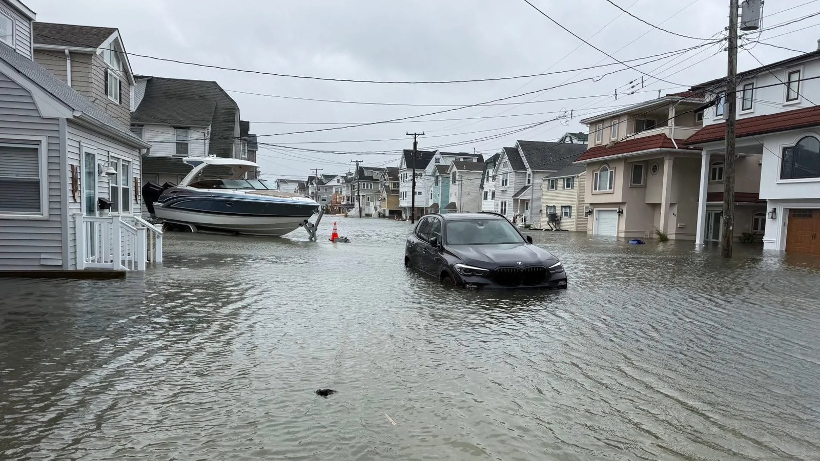 A car sits stuck in floodwater in the middle of West 17th Street in Ocean City during the September 2026 nor'easter, with homes lining both sides of the street.