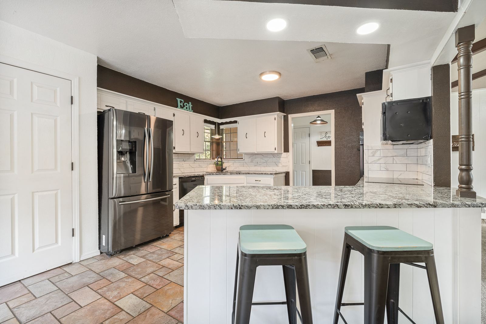 Kitchen with bar-top seating, granite countertops and refrigerator at 3309 Burrus Place Amarillo TX