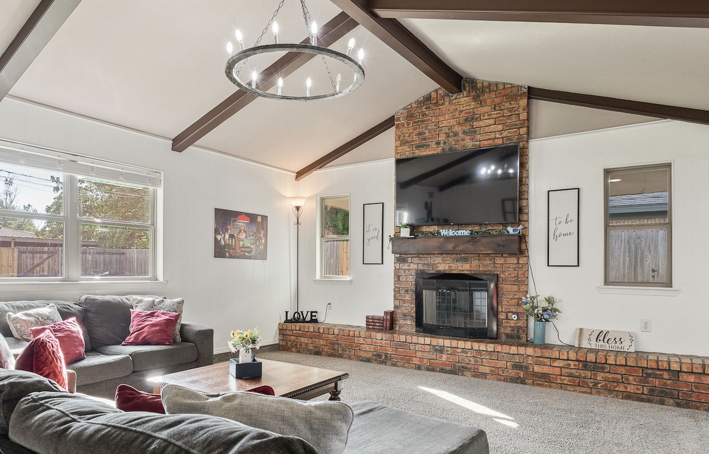 Living room with vaulted ceiling, exposed wood beams and floor-to-ceiling brick fireplace at 3309 Burrus Place Amarillo TX