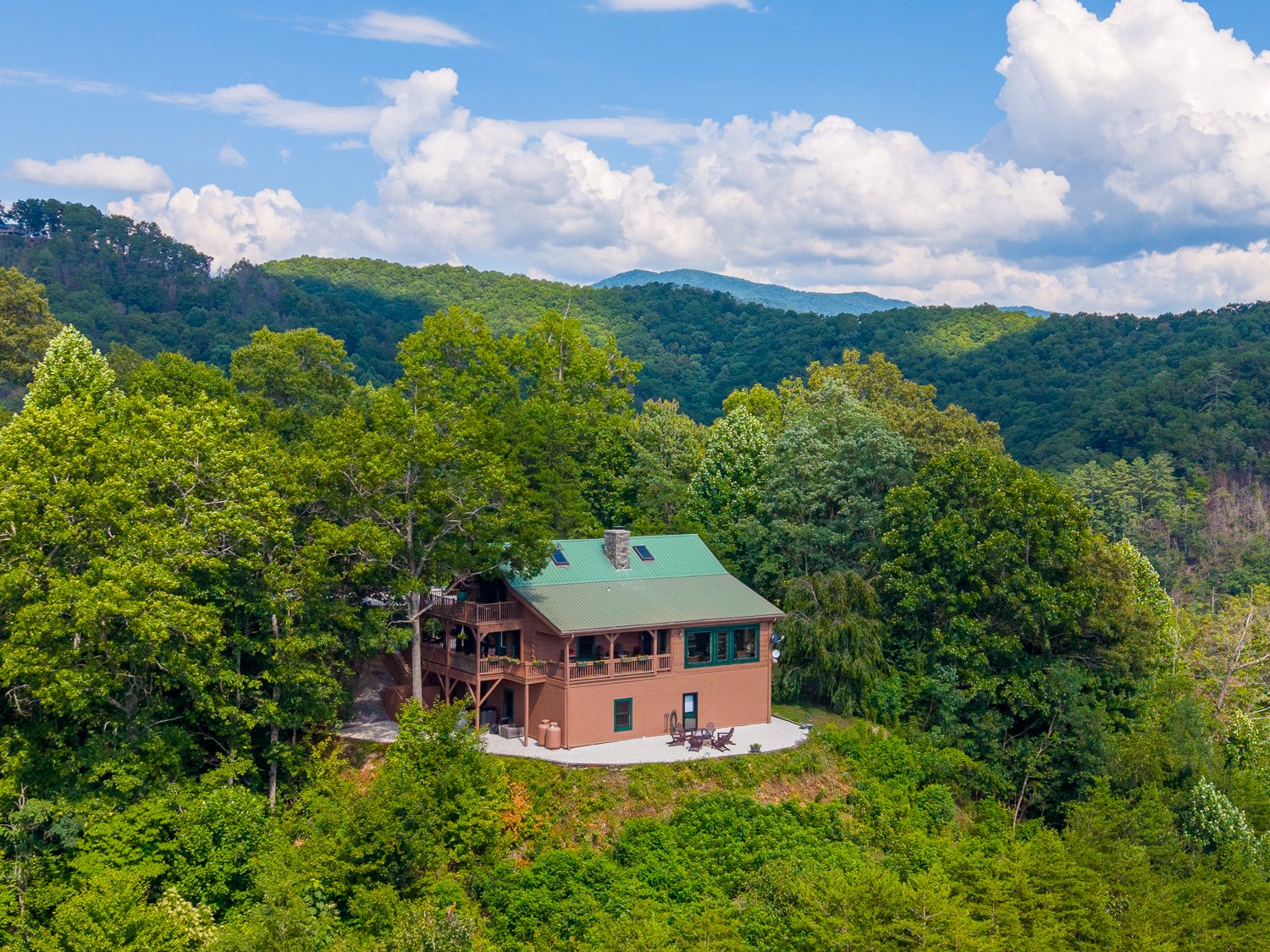Aerial view of 220 Ridge Top Drive in Bryson City, NC, a log home on a wooded ridge-top knoll with mountain ridges beyond