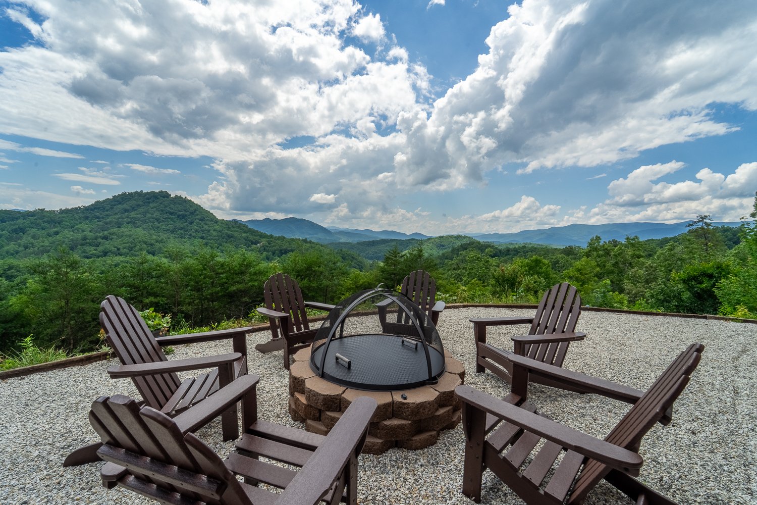 Fire pit ringed by Adirondack chairs with mountain views