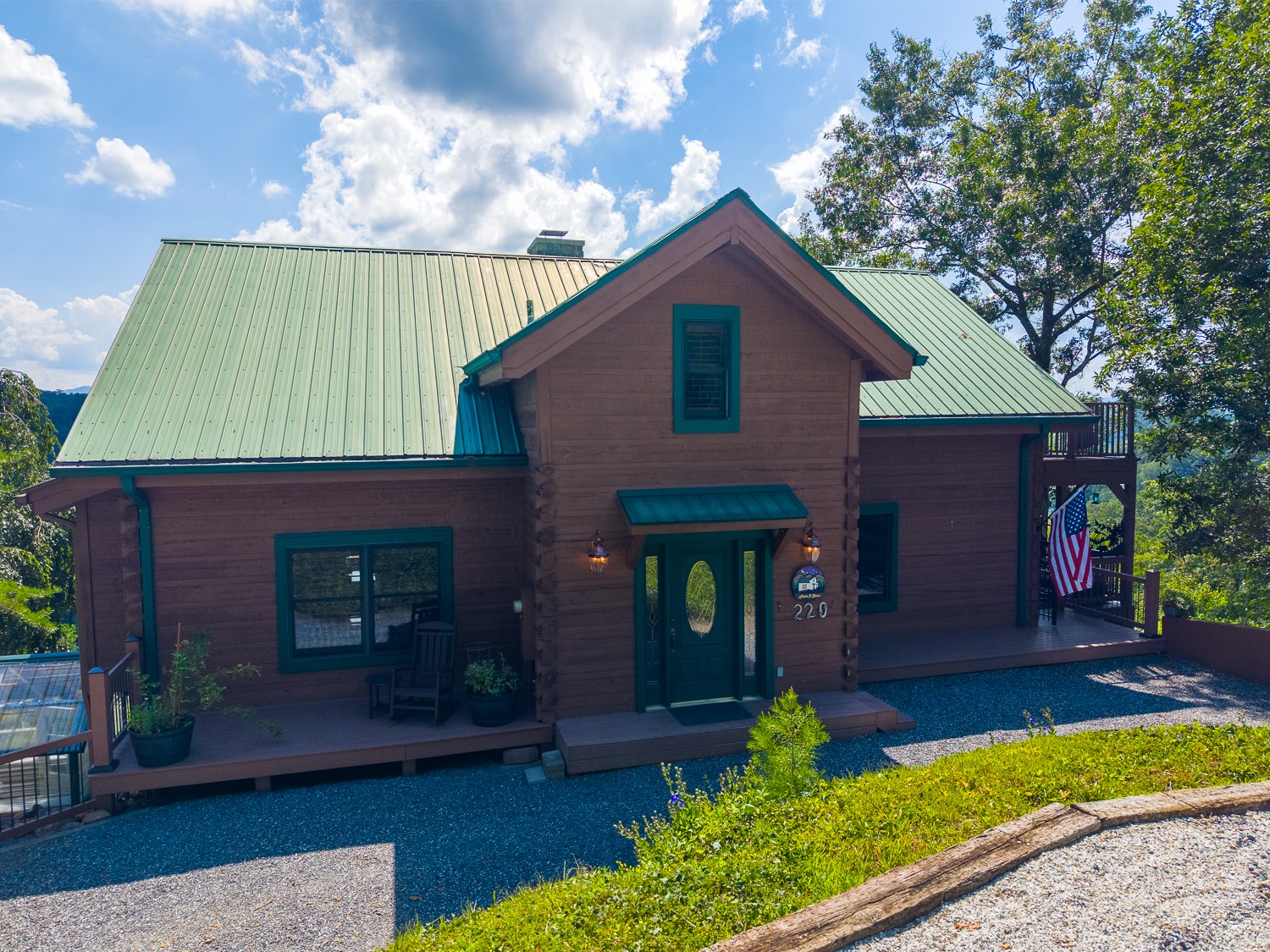 Front of the home with a green metal roof and gravel drive