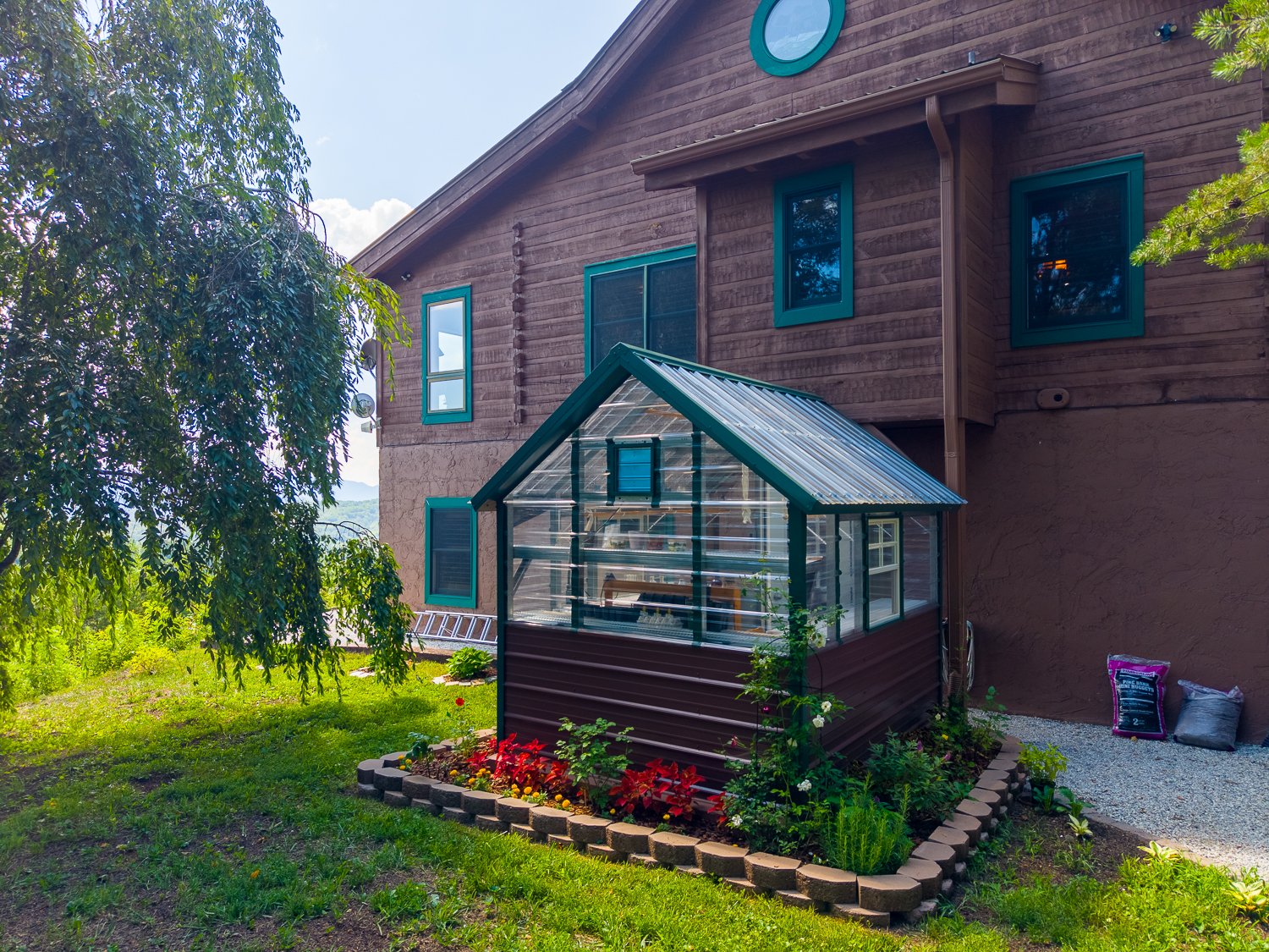 Greenhouse beside the log home, added with its own 30-amp service