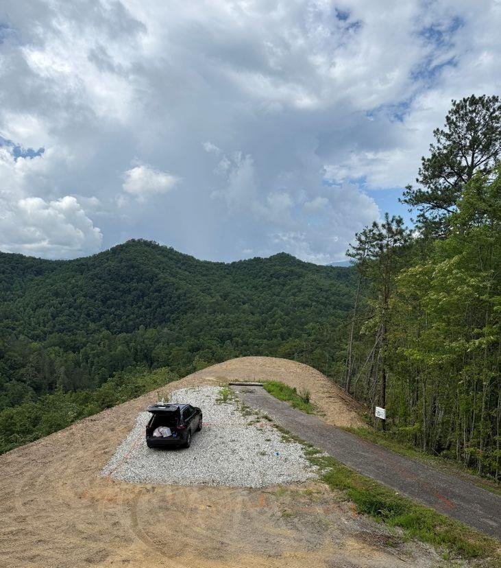 Graveled building pad at 275 Overlook Ridge Road in Bryson City, NC, beside the paved road with a forested mountain ridge beyond