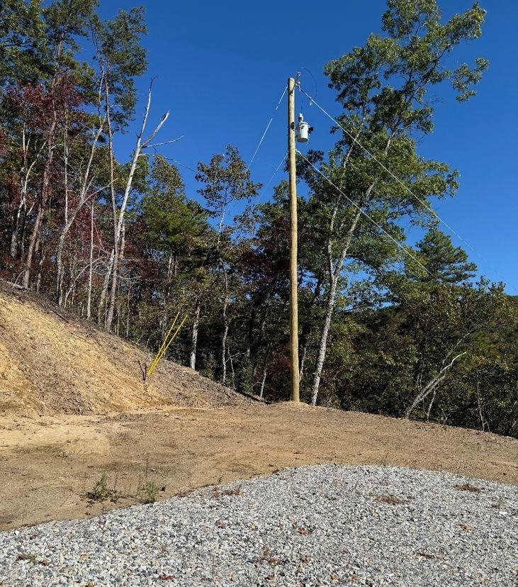 New utility pole with a transformer at the edge of the woods beside the graveled pad