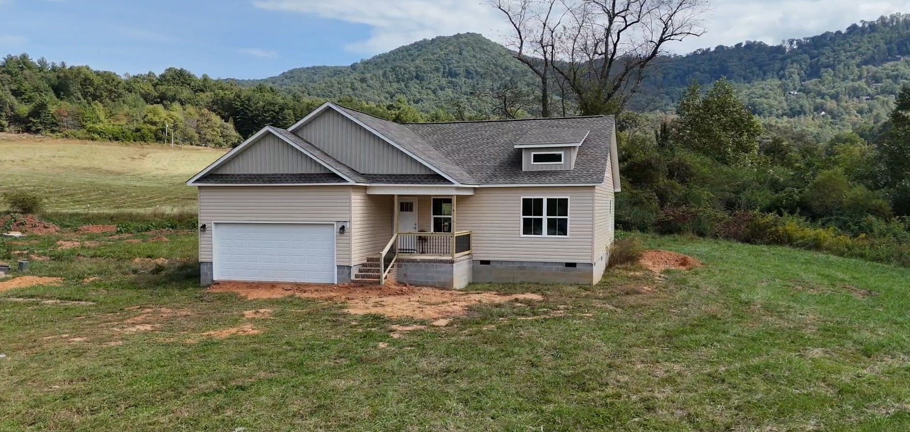 New Charlotte plan home with a two-car garage and covered front porch at 53 Meadow Ridge Road in Franklin, NC, with mountains behind
