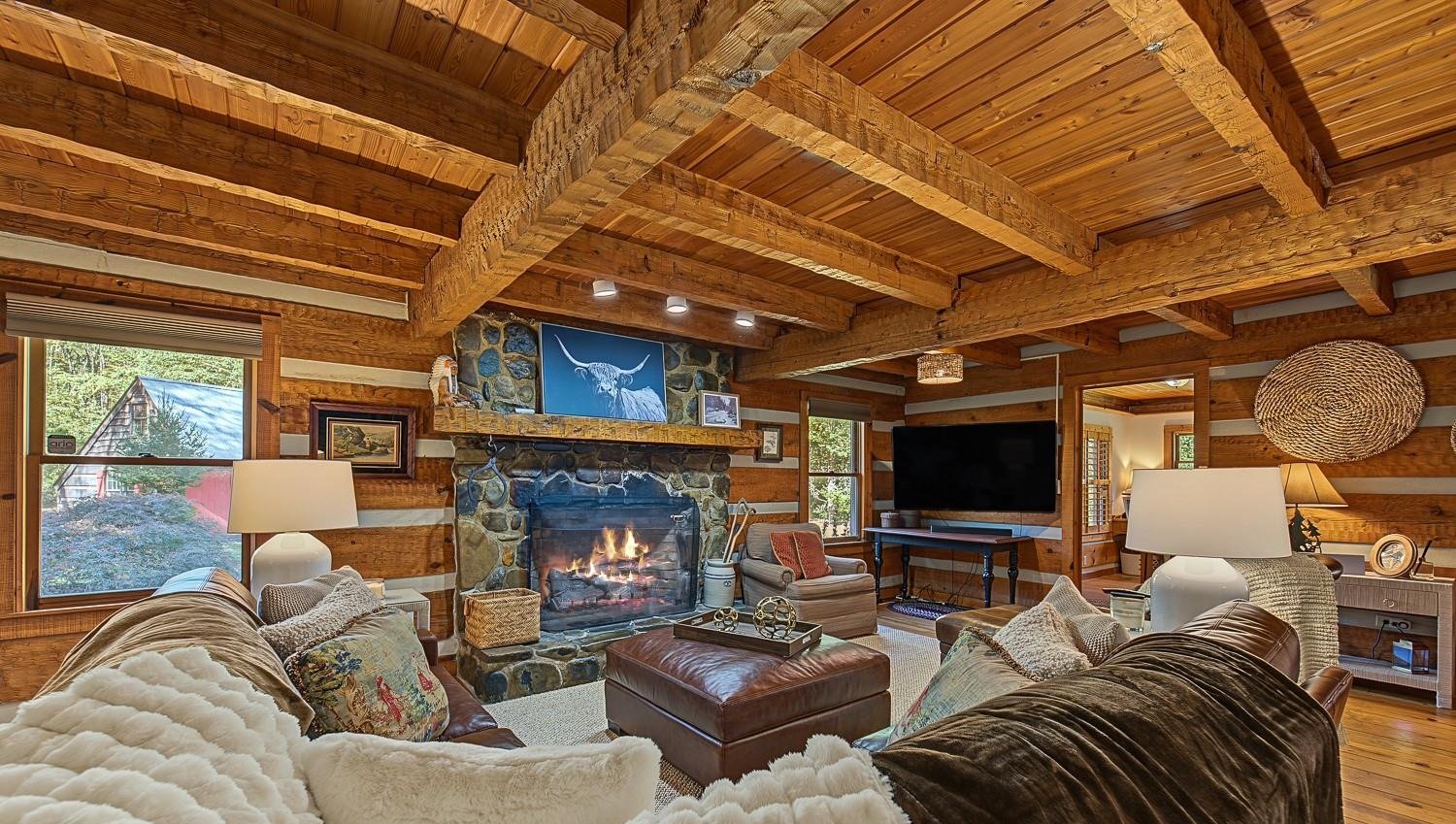 Great room at 7810 Little Snowbird Road with a stone fireplace, gas logs and exposed beams
