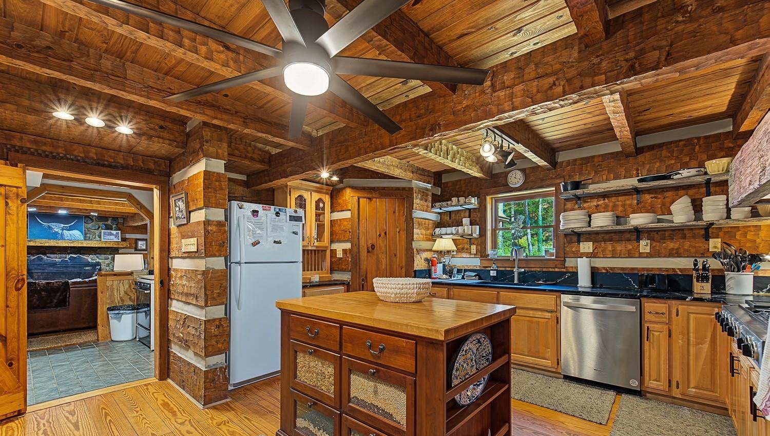 Kitchen with a butcher-block island, pine cabinetry and stainless dishwasher under a beamed ceiling