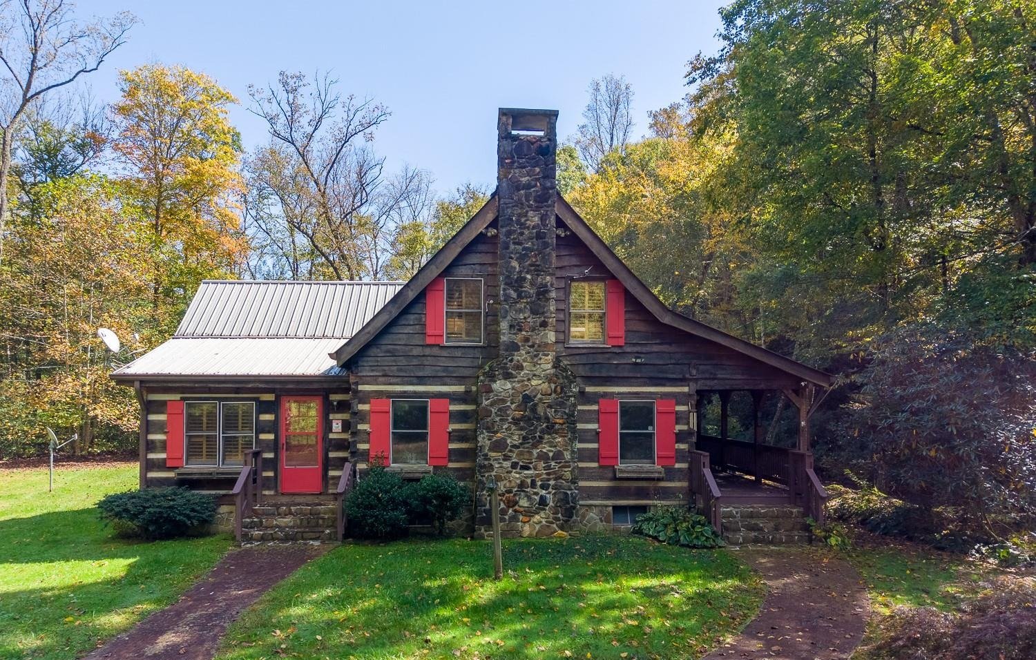 Log cabin with red shutters and a stacked-stone chimney at 7810 Little Snowbird Road in Robbinsville, NC
