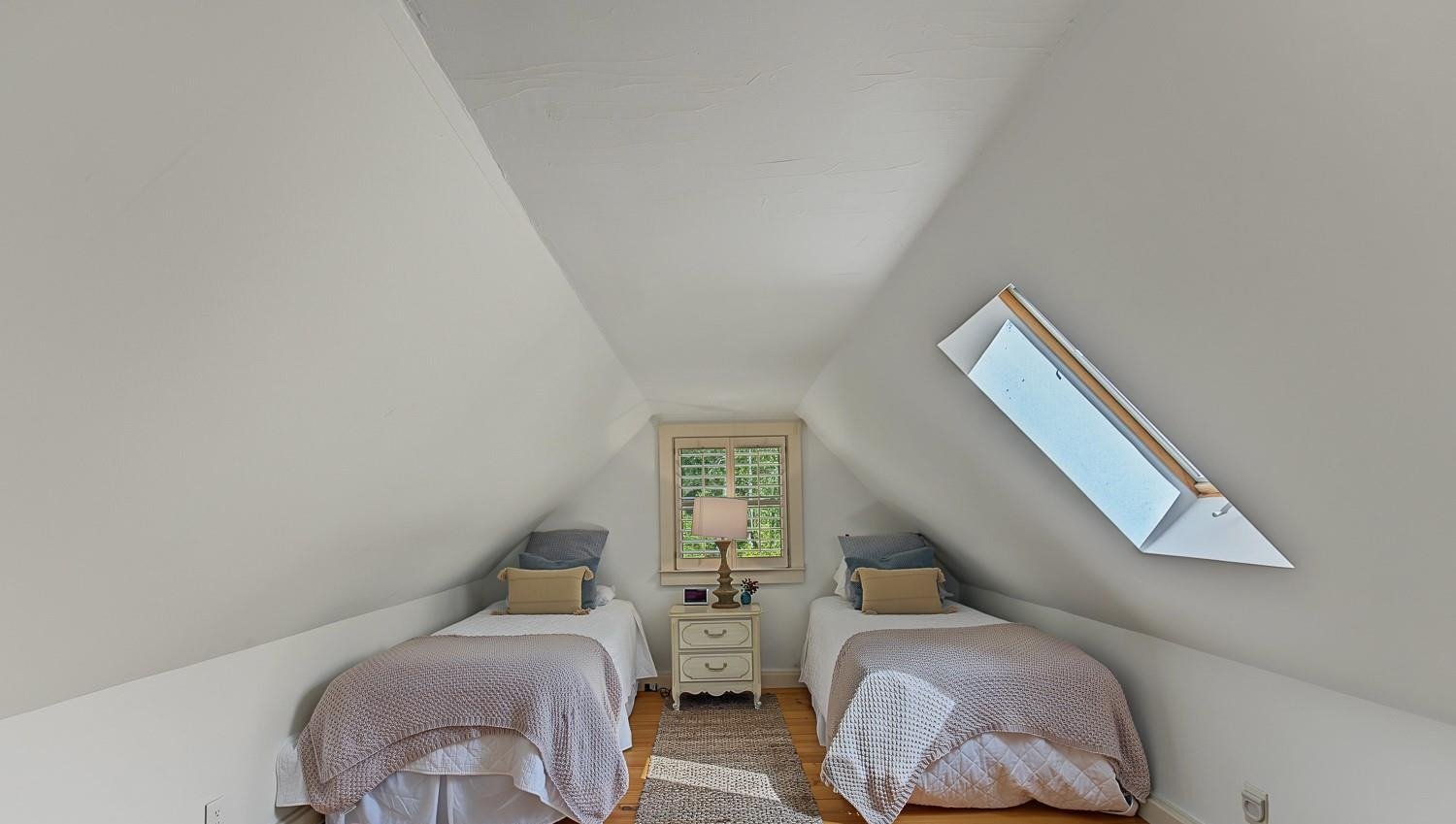 Upstairs room with twin beds under a sloped ceiling and skylight