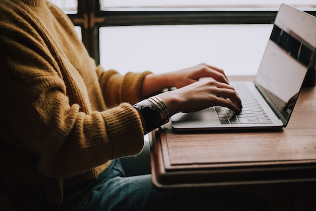 Person in a yellow sweater typing on a keyboard