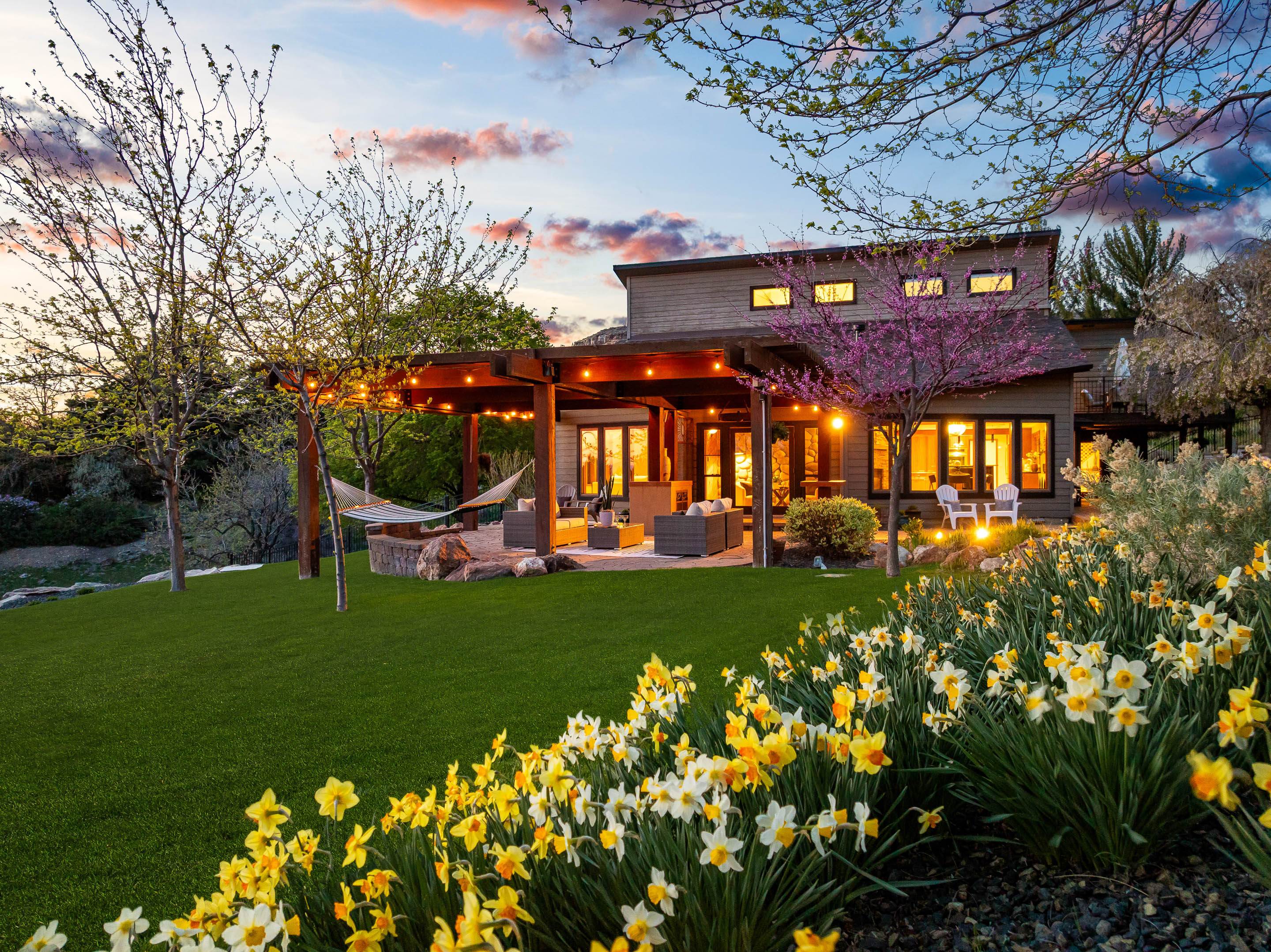Luxury Boise Idaho home with covered outdoor living space, landscaped backyard, and spring flowers at sunset in the Treasure Valley.