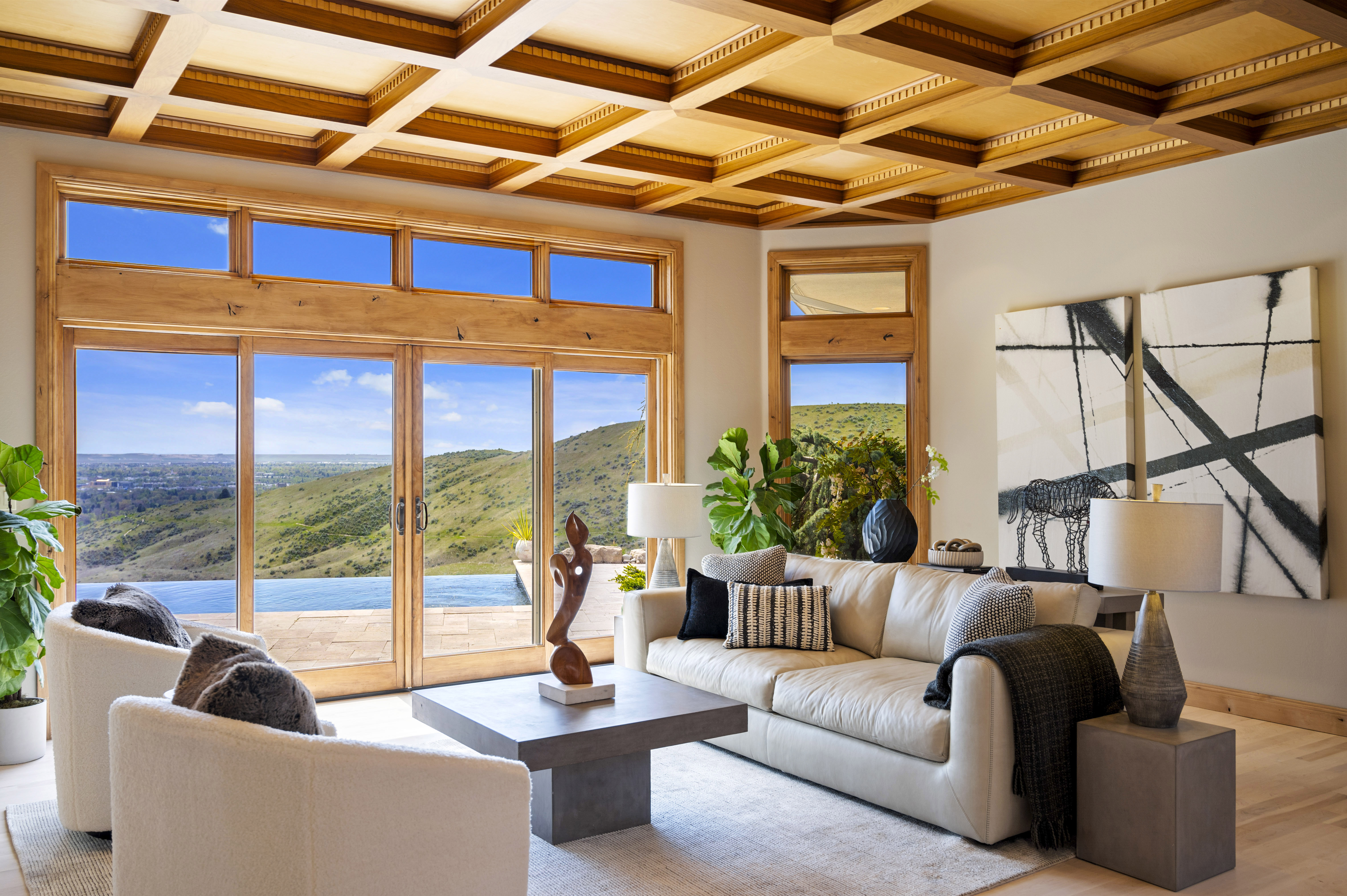 Professionally staged luxury living room with large windows, wood beam ceiling and foothill views in Boise, Idaho.