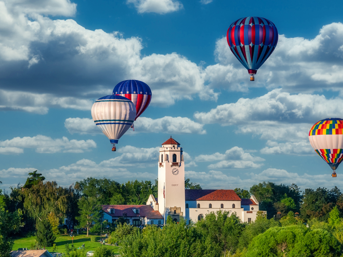 Hot air balloons flying over the Boise Depot beneath clear blue skies in Boise, Idaho.