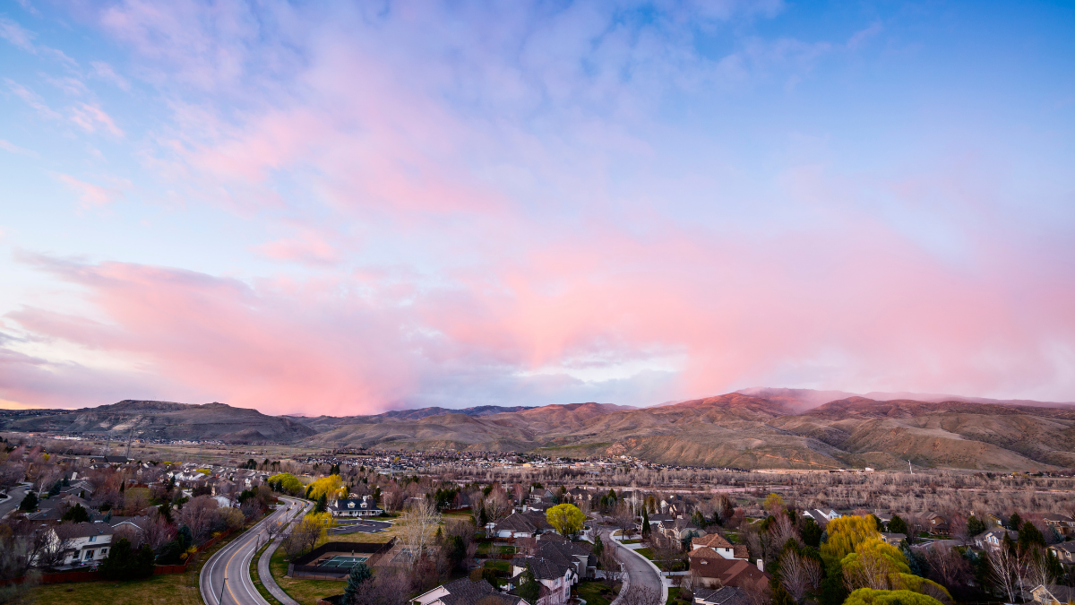 Sunset over a Boise Idaho neighborhood with foothills in the background and residential homes below.