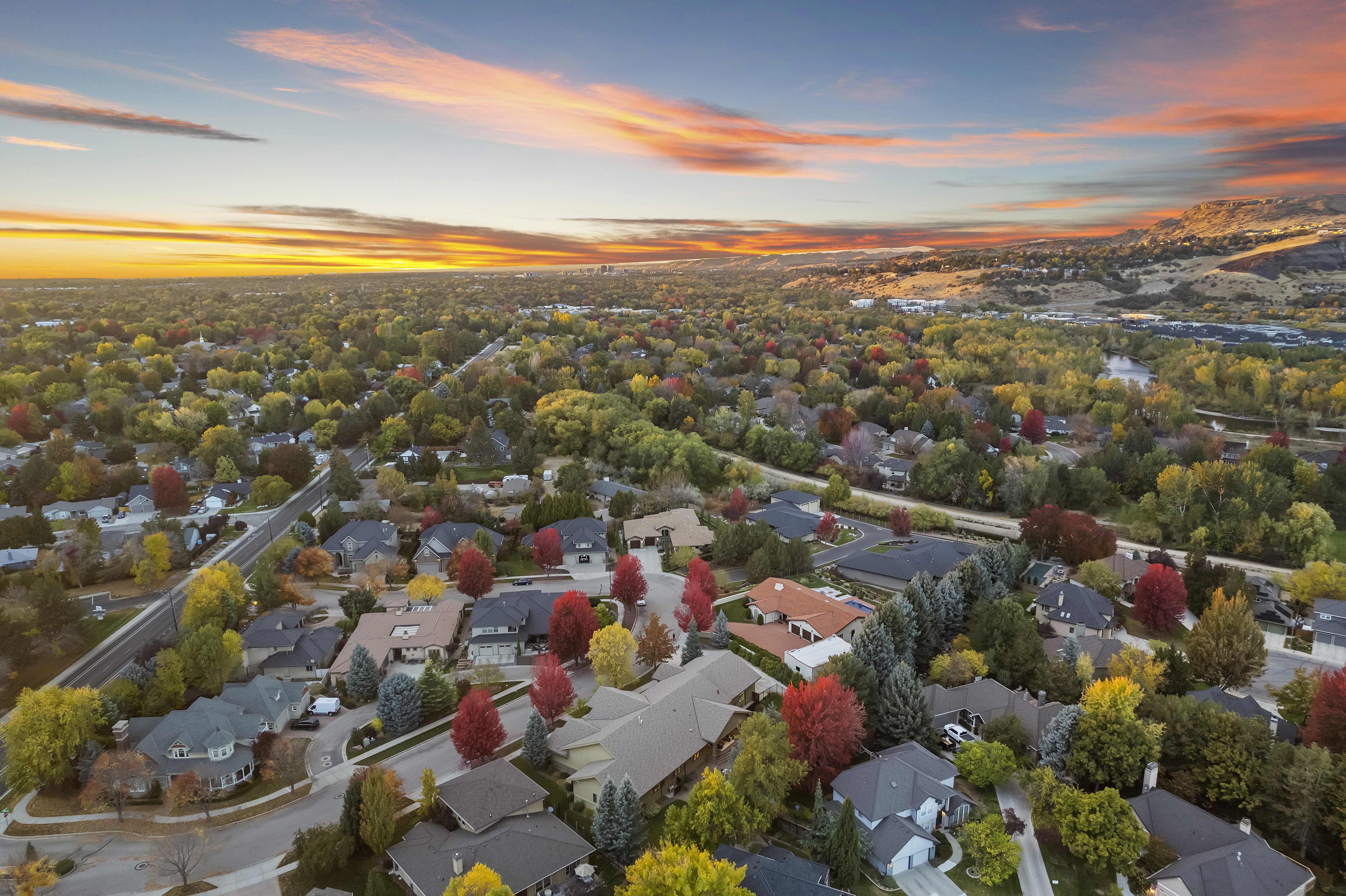 Aerial view of Southeast Boise, Idaho during fall, featuring colorful trees, mature landscaping, and the Boise Foothills at sunset.