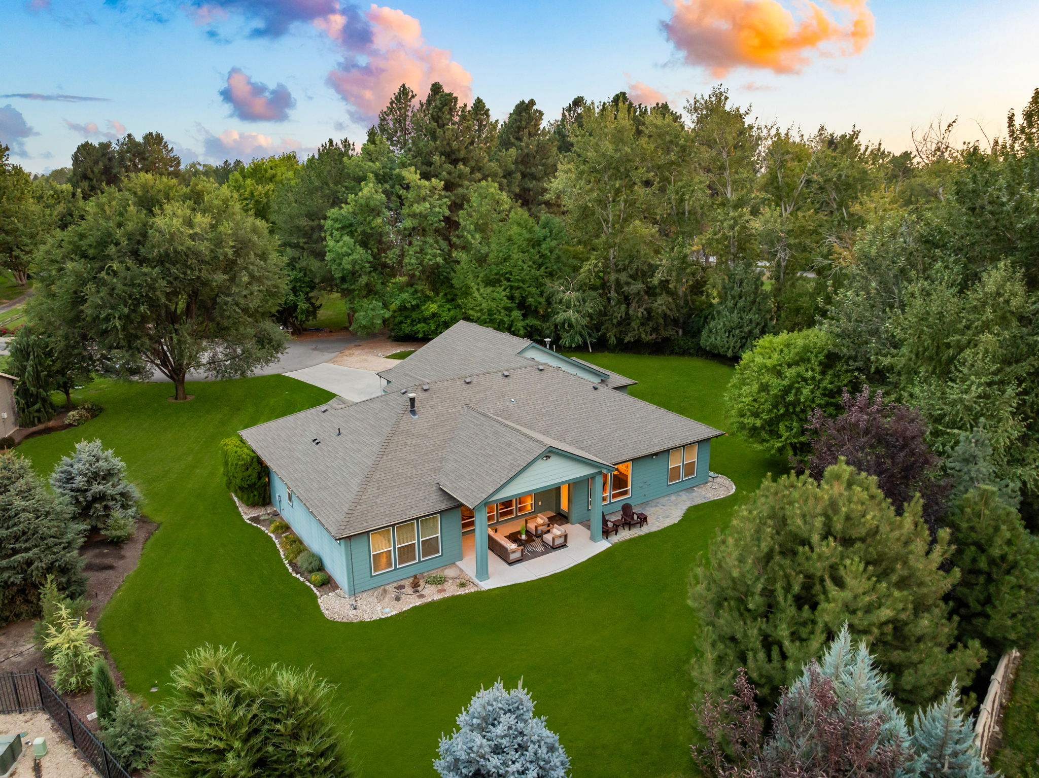 Aerial view of a single-level home surrounded by mature trees and a spacious landscaped yard in Southeast Boise, Idaho.