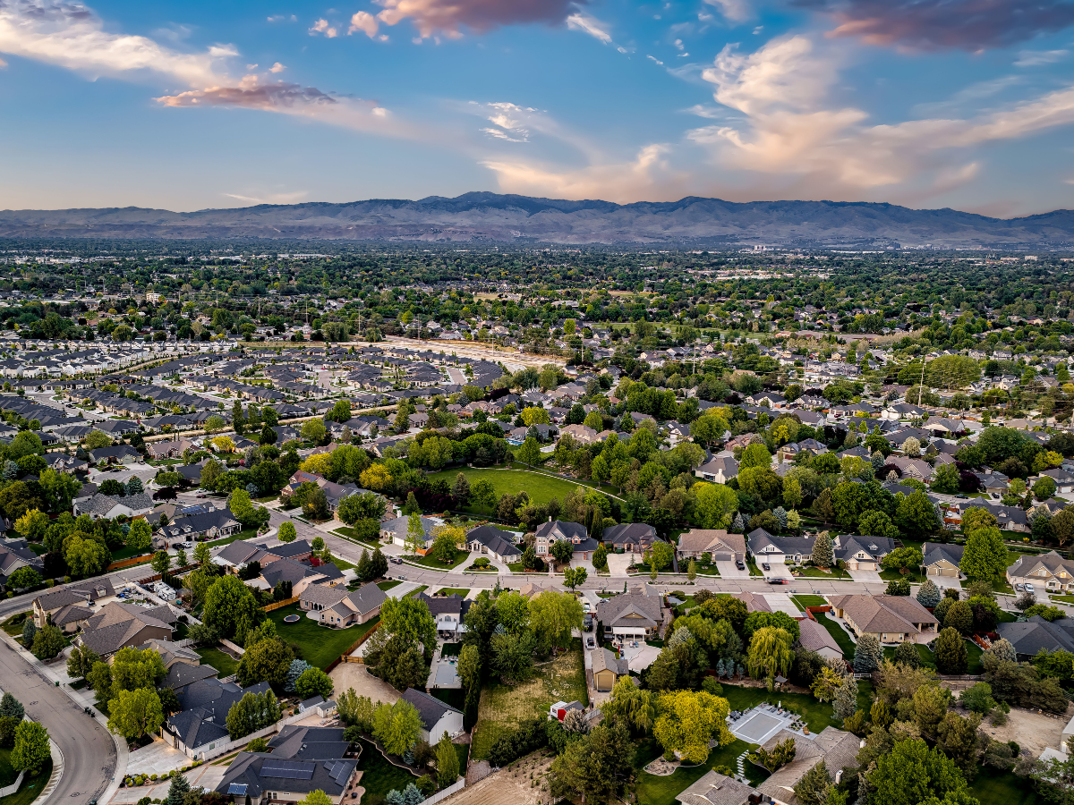 Aerial view of residential neighborhoods in Boise, Idaho, with homes, tree-lined streets, and surrounding scenery.