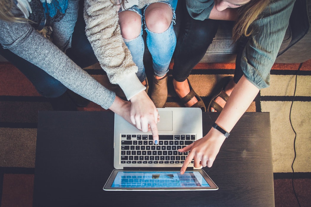 Three women pointing at a laptop.