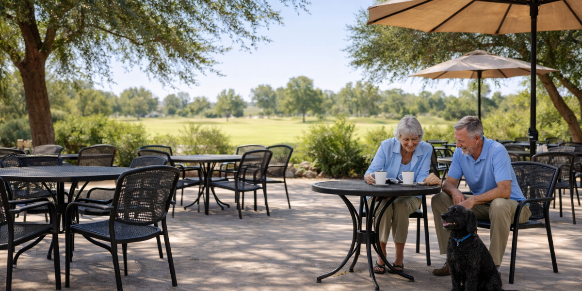 A retired couple eating on a patio with their dog at an onsite restaurant at a 55+ community in mesa