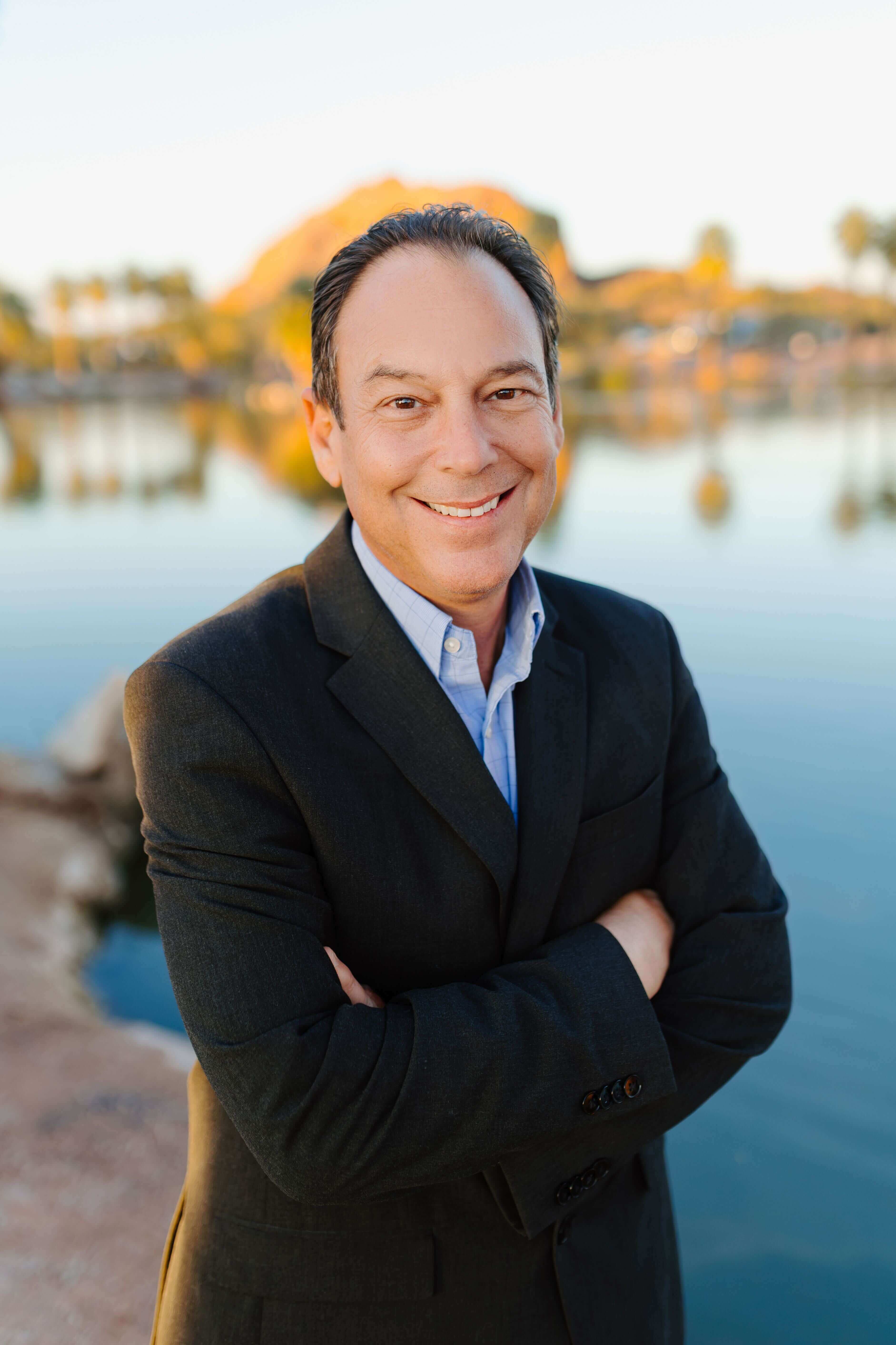 Ron Pacioni an AZ probate real estate agent in a dark suite with a calming backdrop of the arizona sunset