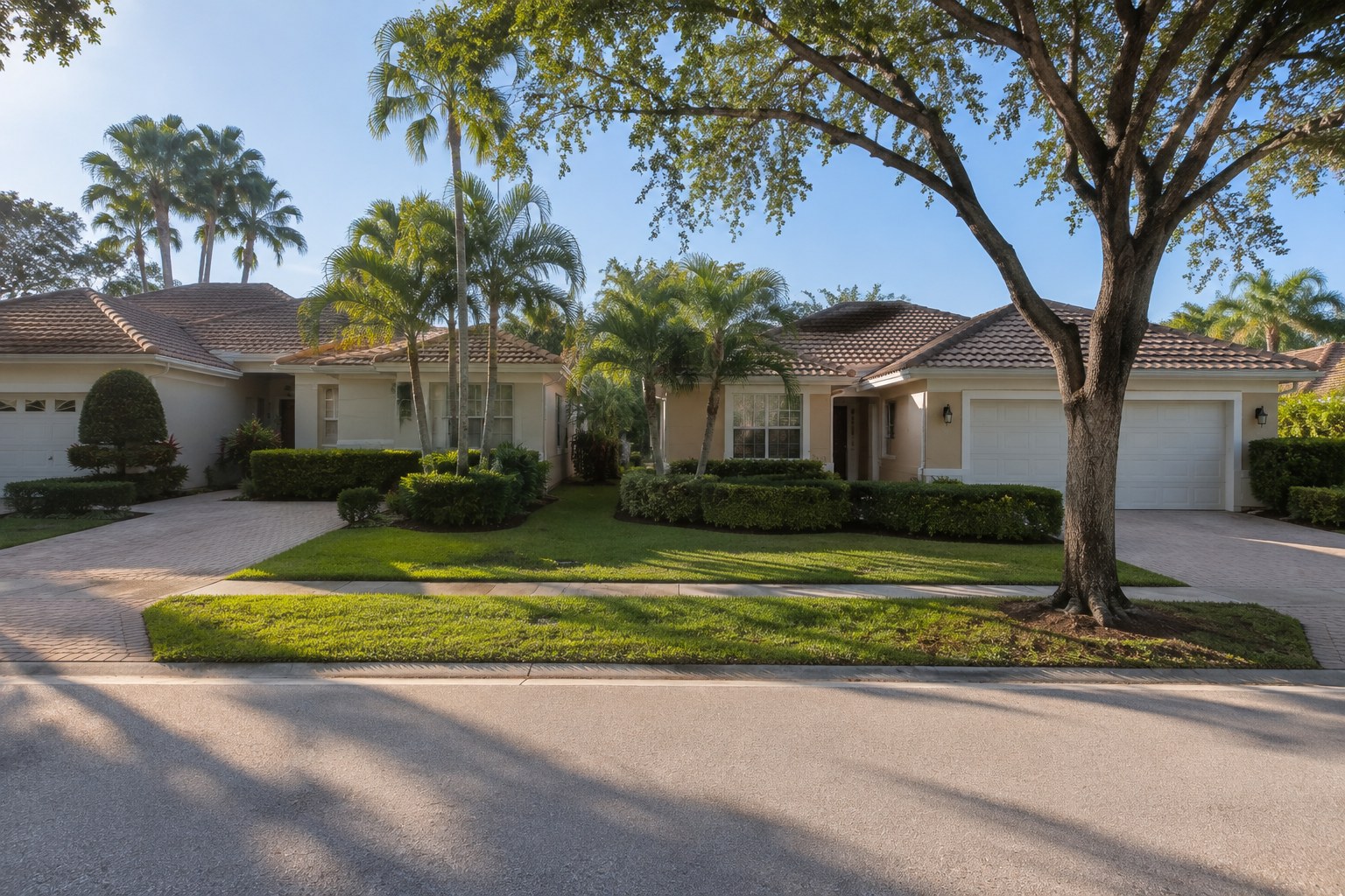 Two similar single-family residences side by side on an established residential street in Palm Beach County, Florida, photographed in soft morning light. The scene accompanies an article on Florida property tax structure and the long-held home &mdash; how the homestead assessment limitation, portability and non-ad-valorem assessments shape what a long-tenured owner actually holds.