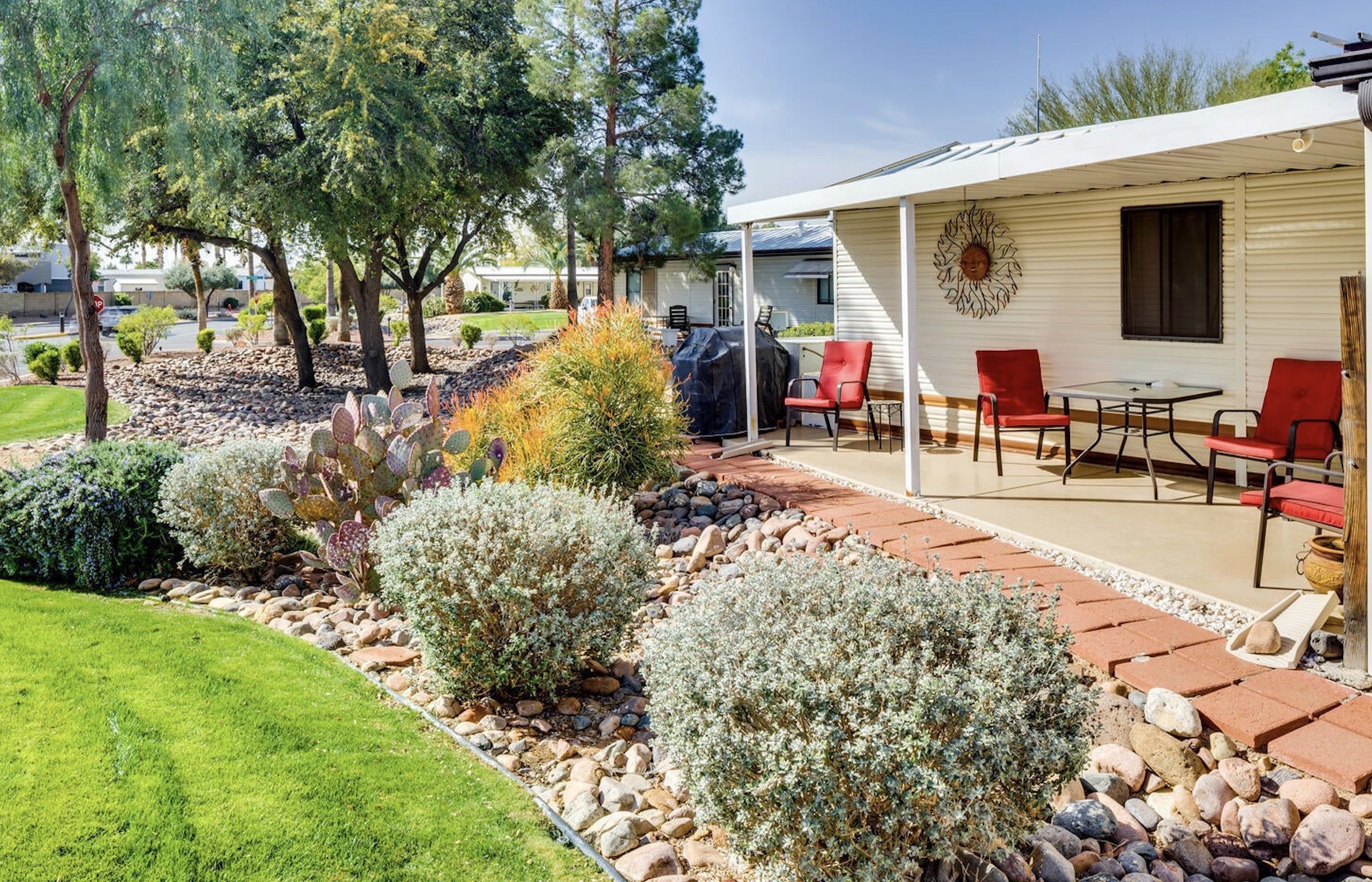 Park model with a covered patio and desert landscaping in Happy Trails Resort in Surprise Arizona