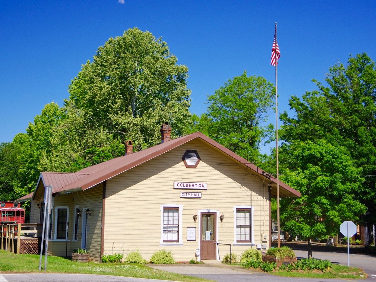 The small yellow historic depot and a red caboose in Colbert, Georgia
