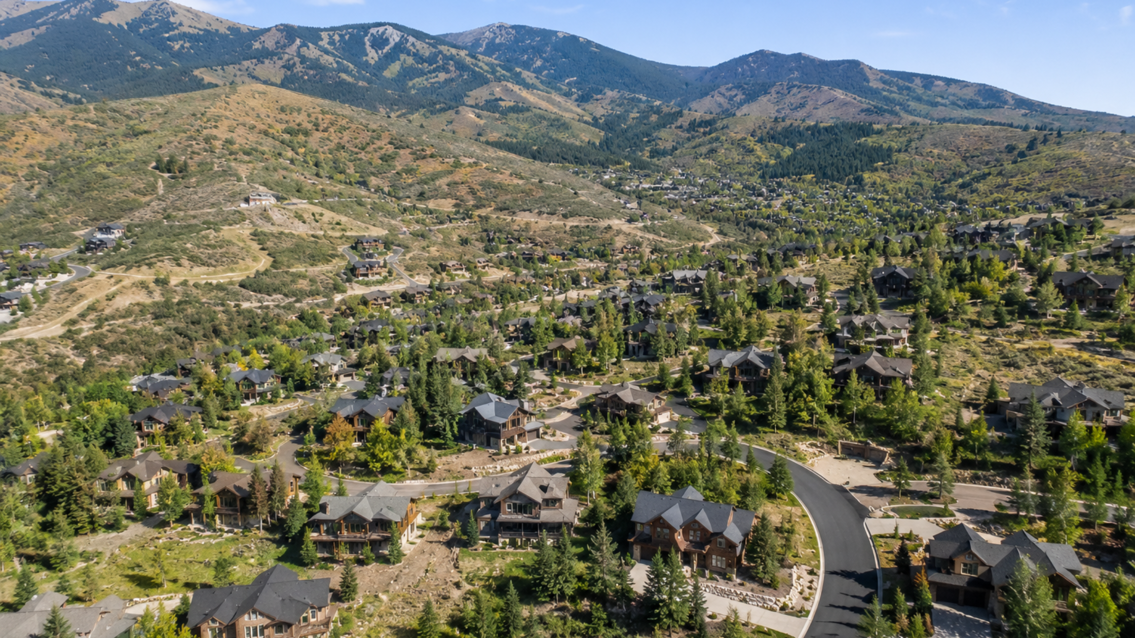 Drone view of a Park City residential community featuring luxury homes, mountain landscapes, and year-round outdoor living