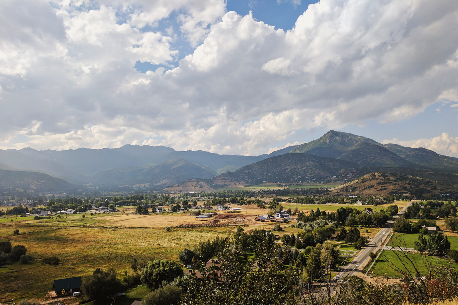 Fields and homes beneath a mountain ridge.